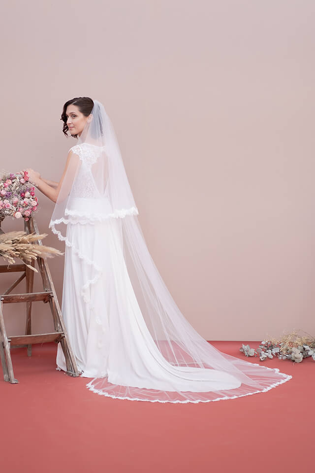 Jeune mariée portant une robe en dentelle dos nu et un voile long en tulle et dentelle
