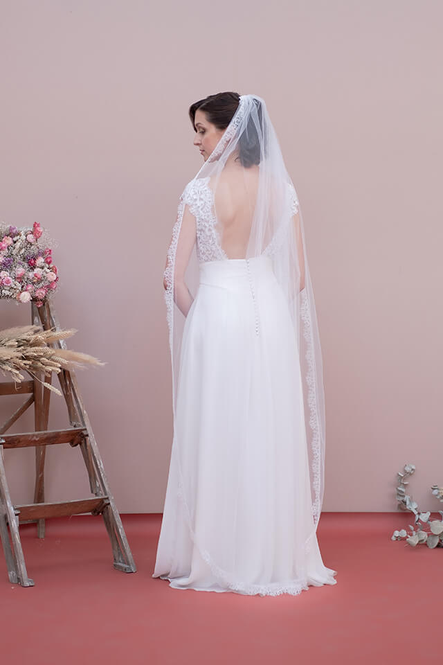 Jeune mariée portant une robe en dentelle et un voile de mariée long en tulle et dentelle