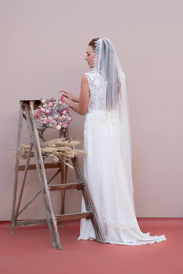 Jeune mariée portant une robe en dentelle et un voile de mariée court en tulle et dentelle