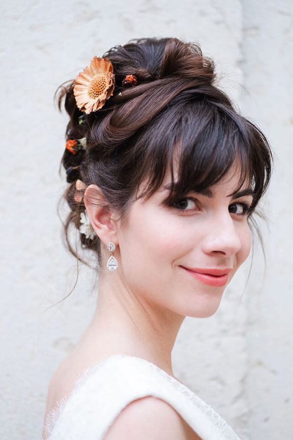 Jeune mariée portant des boucles d'oreilles en formes de goutte en or et strass