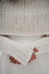 Femme sur fond enneigé en robe de mariée habillée d'un ensemble tricoté avec mitaine en laine angora
