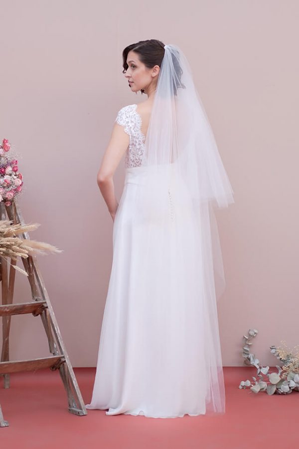 Jeune mariée portant une robe en dentelle dos nu et un voile long en tulle
