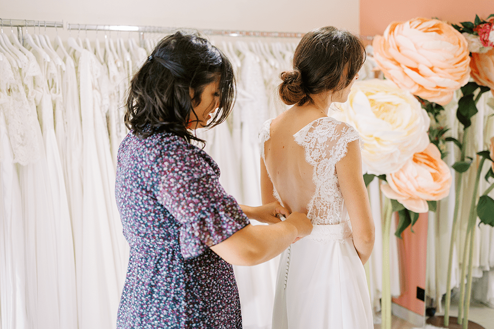 Ajustement d’une robe de mariée vu de dos dans un showroom