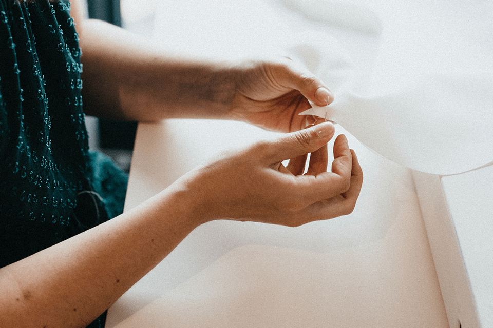 Confection artisanale d’une robe de mariée avec aiguille et dentelle