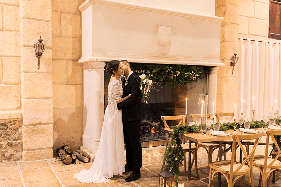 Couple de mariés complices dans un château, table de réception et cheminée