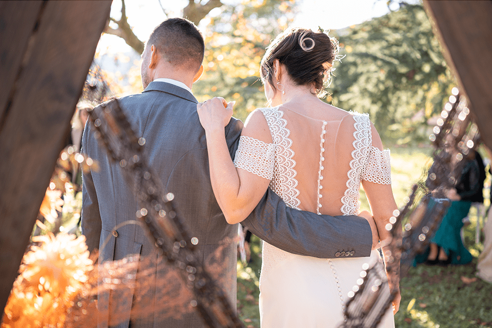 Couple de mariés de dos se tenant par la taille en plein air