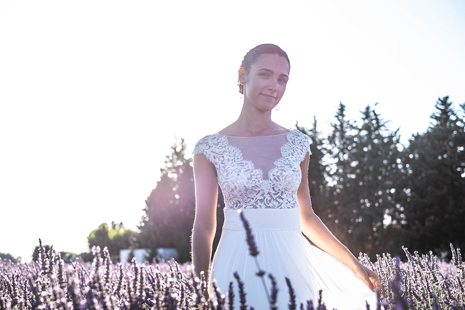 Femme en robe de mariée transparente dans un champ de lavande