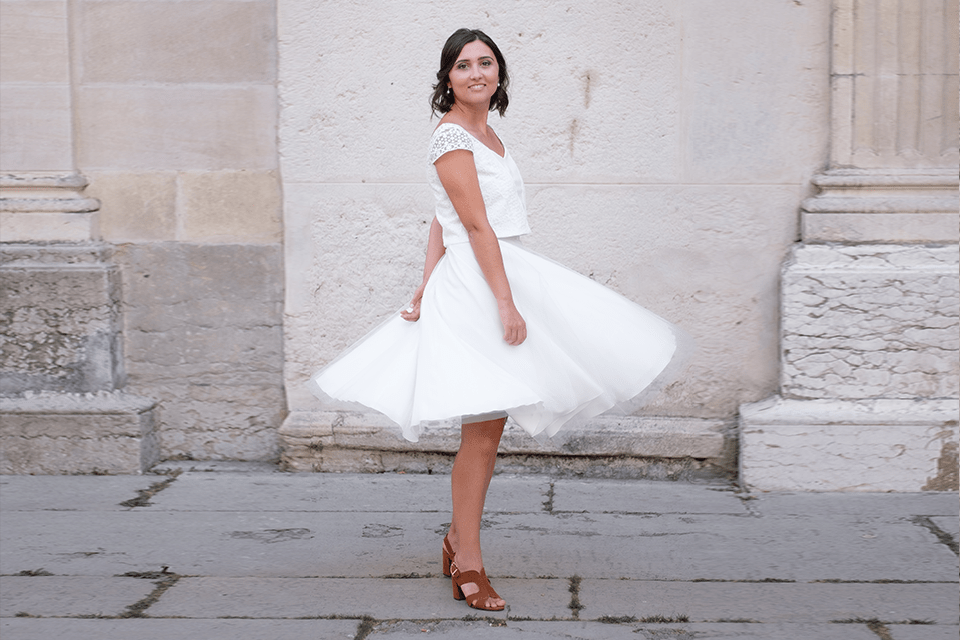 Jeune femme en robe courte tournant devant un mur extérieur