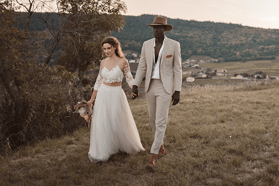 Femme en robe de mariee epaules denudees et mari avec chapeau dans une plaine