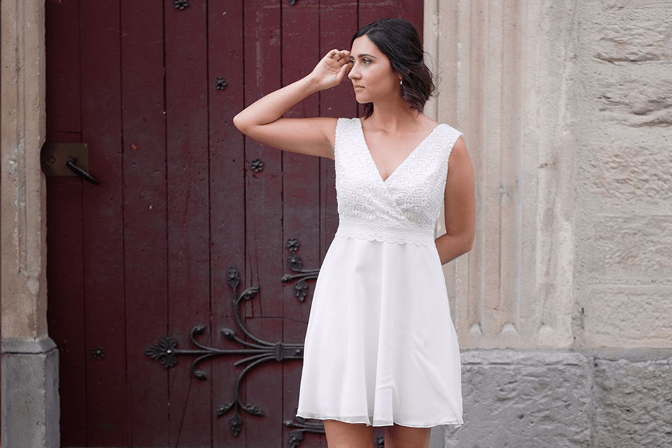 Mariée en robe courte ajustant une mèche de cheveux