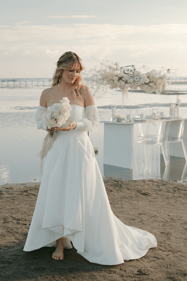 Mariée en robe de mariée sur une plage décorée de fleurs