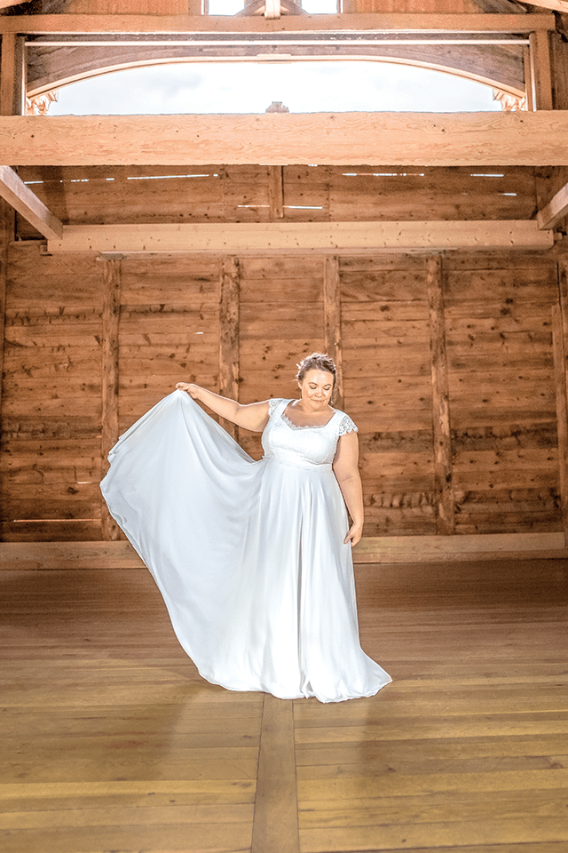 Mariée ronde tenant la jupe de sa robe de mariée