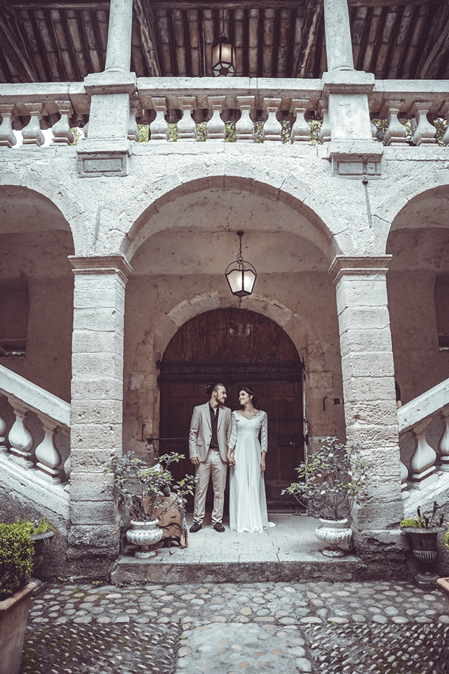 Mariée en robe de mariée sur-mesure devant un château provençal avec arcades en pierre, mariage chic