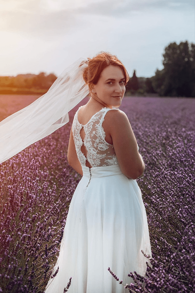 Femme en robe de mariée au haut transparent dans un champ de lavande au coucher du soleil