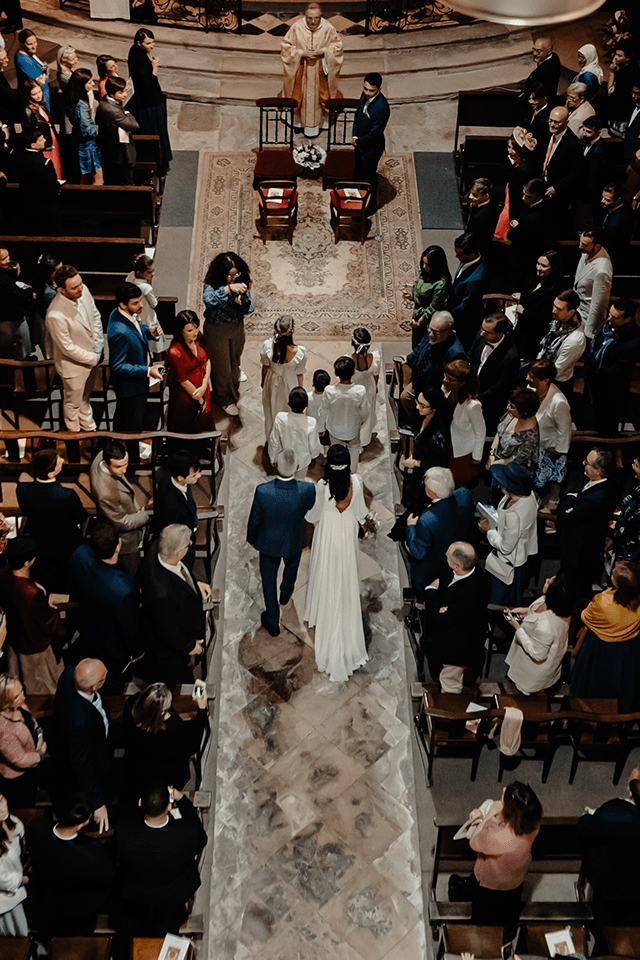 Cérémonie de mariage à l’église, mariée avançant avec son père entourée d’invités