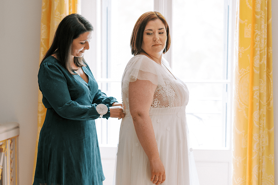 Créatrice fermant une robe de mariée dans le dos
