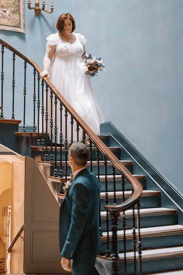 Marié attendant sa femme en robe descendant un escalier
