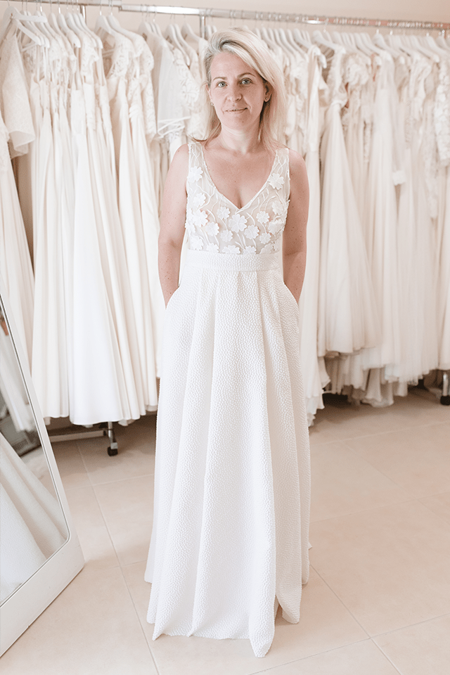 Femme blonde essayant une robe de mariée dans un showroom