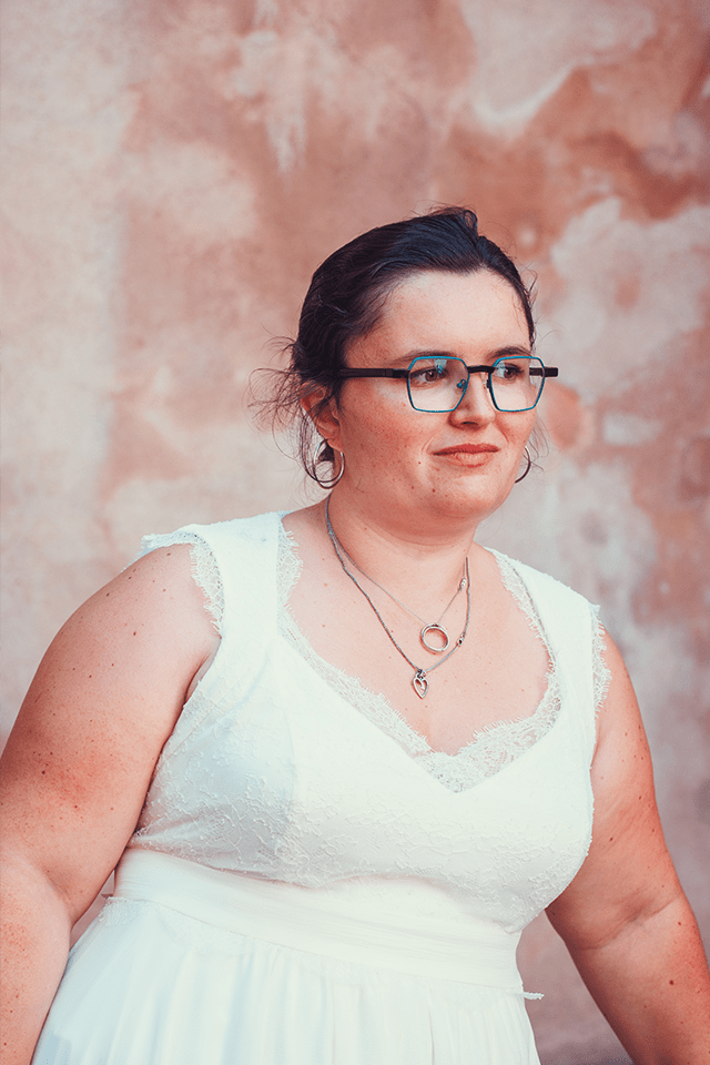 Jeune femme ronde en robe de mariée sans manches et lunettes