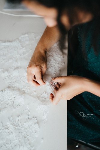Finition à la main d’une dentelle pour robe de mariée sur-mesure chez Kaa Couture