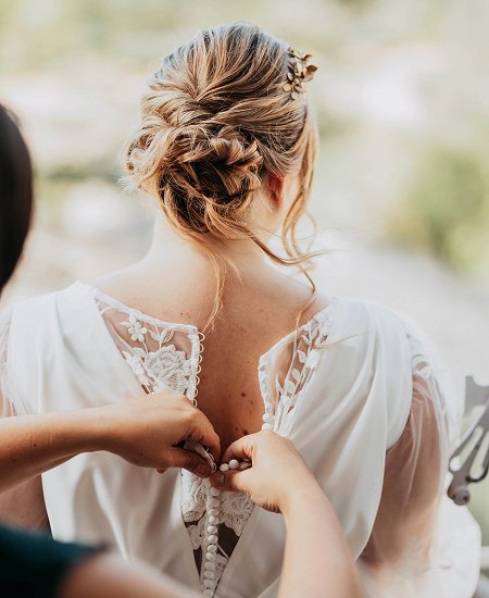 Vue de dos d'une robe de mariee sur mesure grande taille en train d’être boutonnée, détails de dentelle apparents