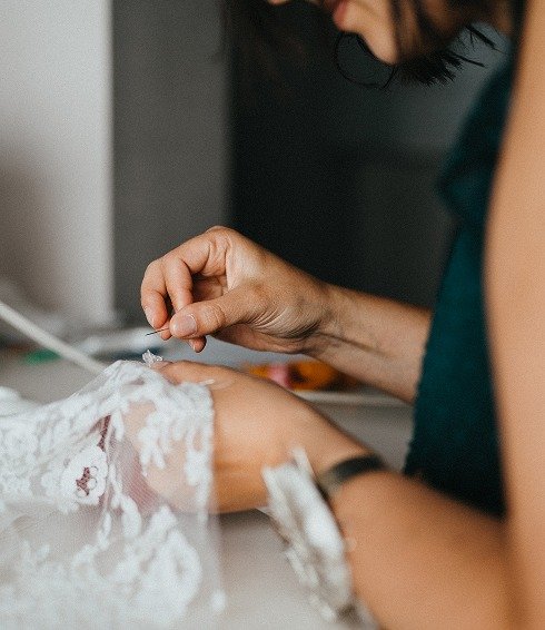 Broderie à la main sur une dentelle délicate lors de la confection sur-mesure d’une robe de mariée dans l’atelier Kaa Couture