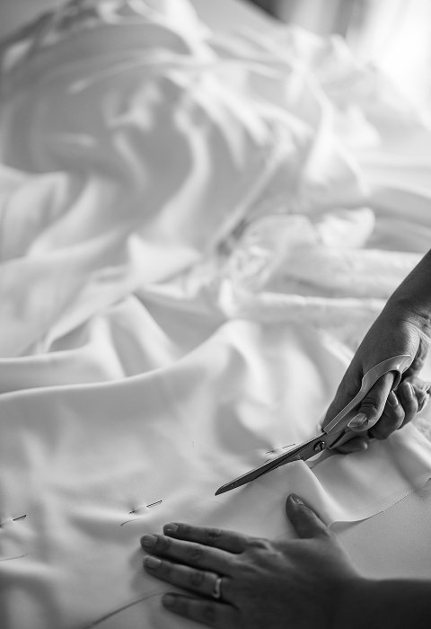 Découpe d’un tissu blanc à la main dans l’atelier Kaa Couture pour la confection artisanale d’une robe de mariée sur-mesure