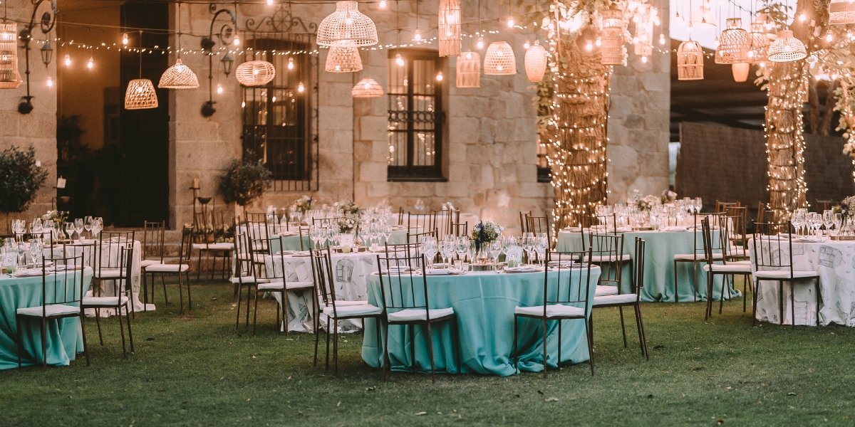 Dîner de mariage en extérieur avec tables dressées et guirlandes lumineuses