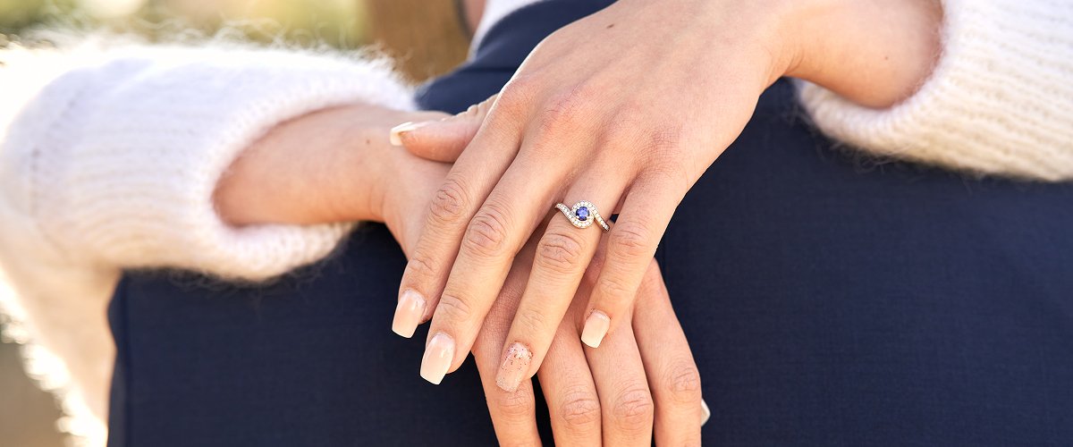 Gros plan sur les mains d’une mariée avec une bague de fiançailles sertie d’un saphir et diamants