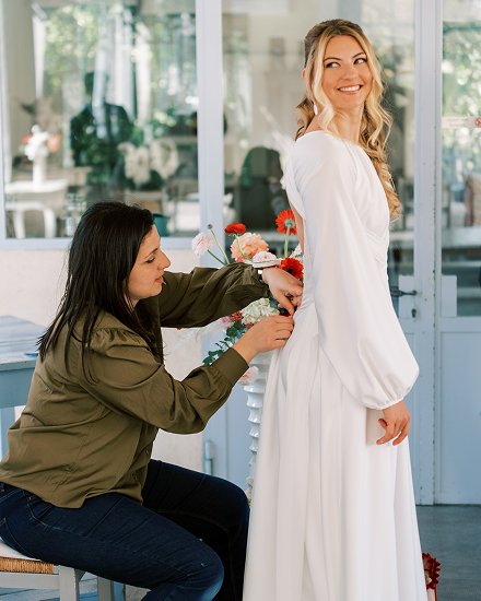 Ajustement du dos de la robe de mariee d'une femme blonde pour son mariage