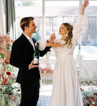 Couple de mariées celebrant leur mariage avec du champagne dans un cadre floral