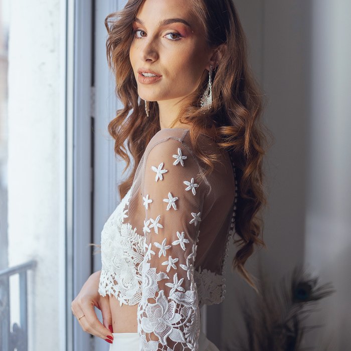 Femme elegante au regard mysterieux portant une robe de mariee avec un haut transparent et des motifs