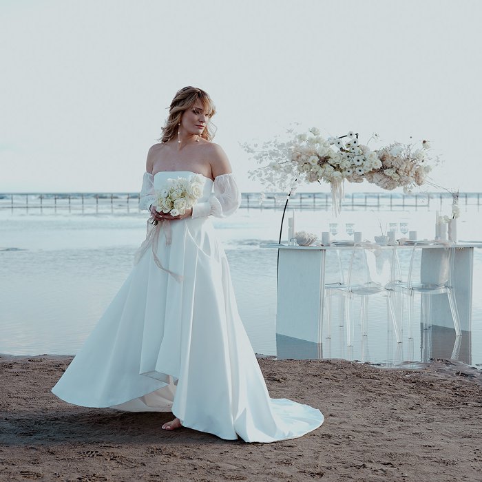 Femme en robe de mariee sur une plage dans une ambiance poetique